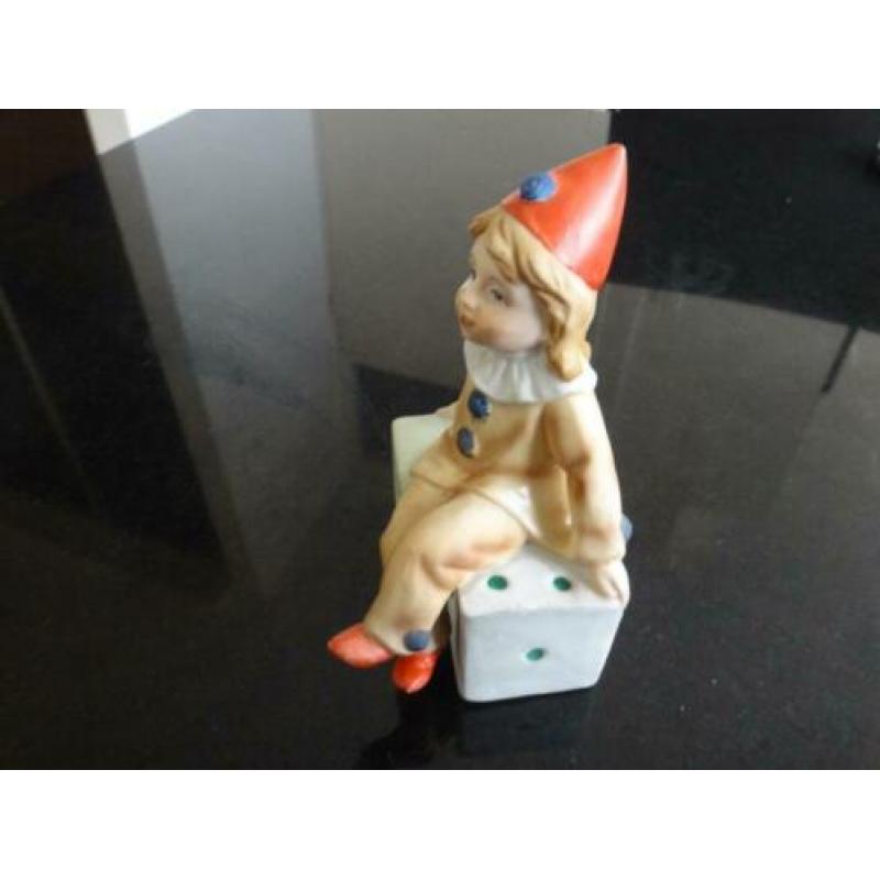 beeldje, pierrot, clown, zit op 2 dobbelstenen, rode muts