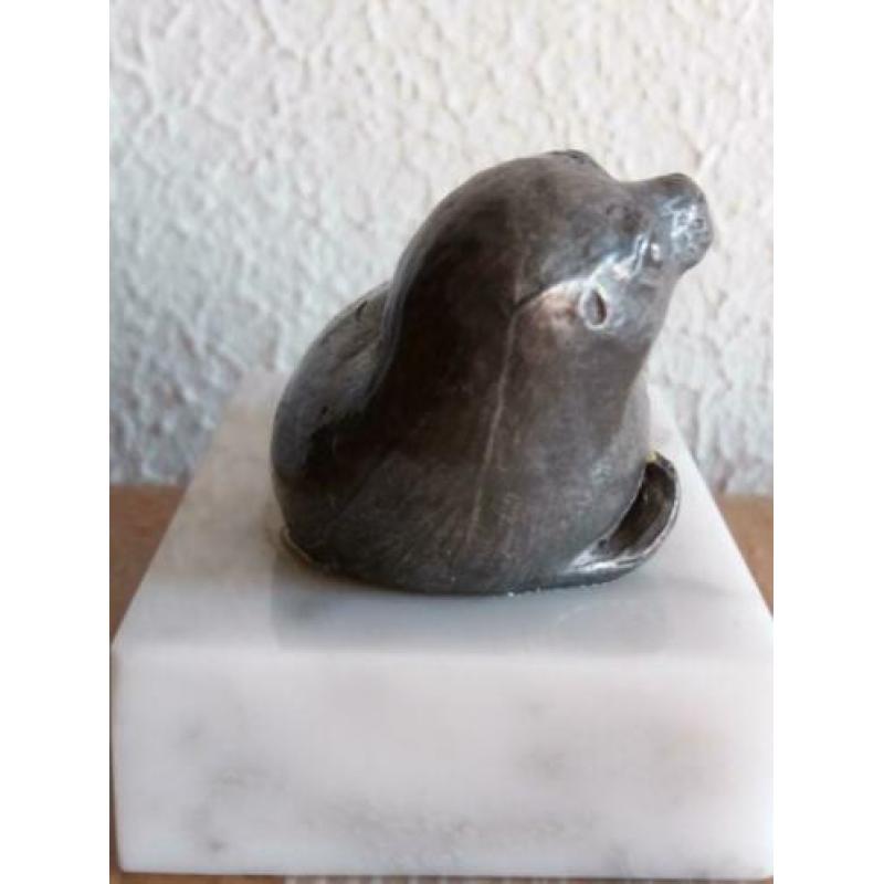 Tinnen zeehondje op een marmeren ondergrond.