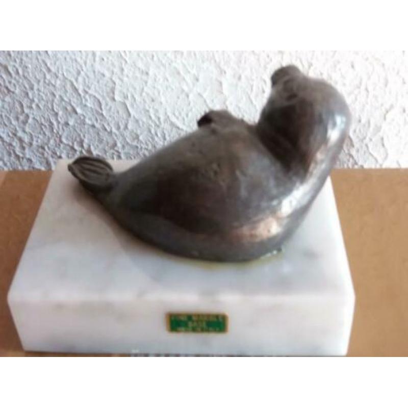 Tinnen zeehondje op een marmeren ondergrond.